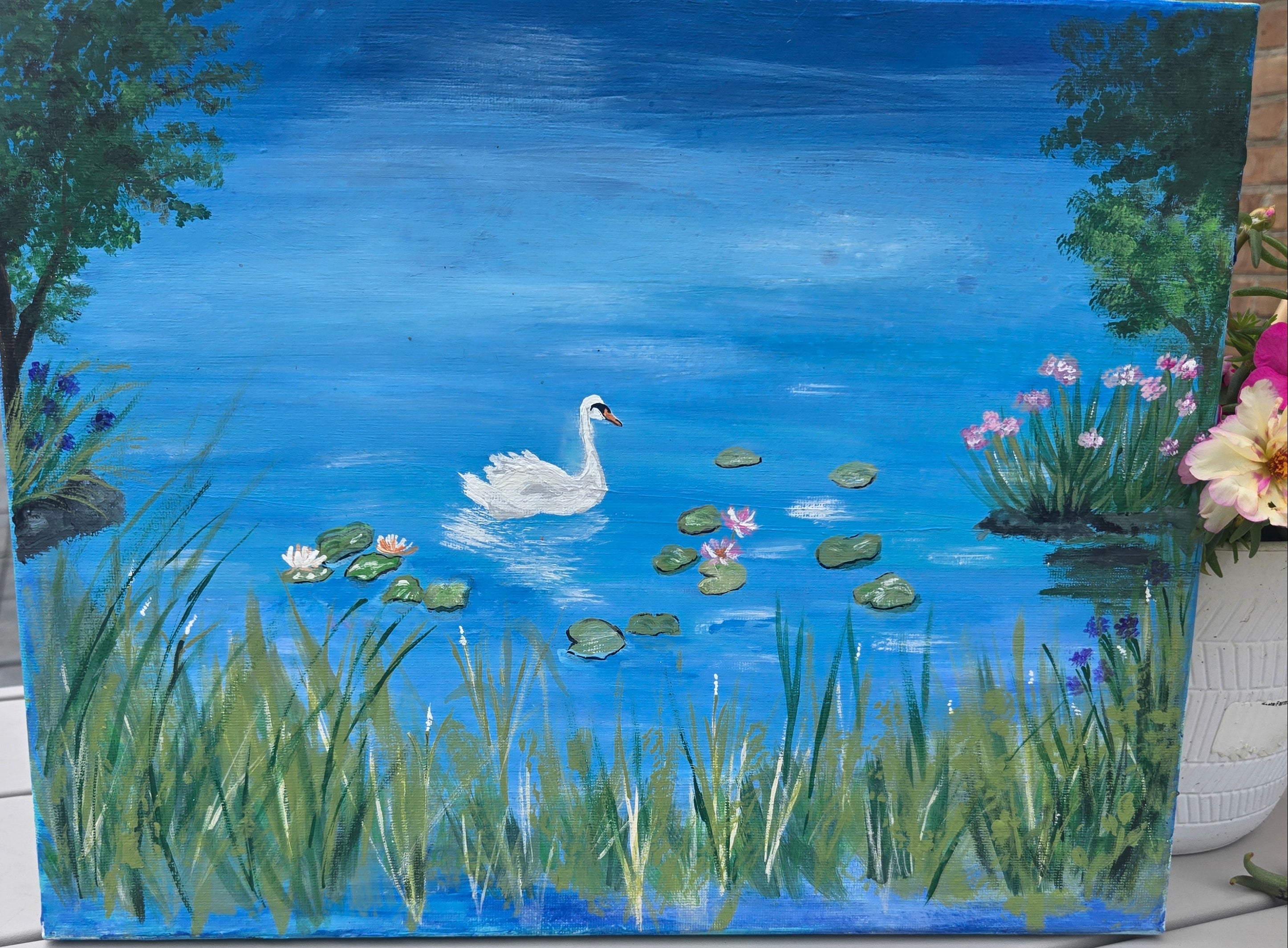11x14 inches Painting of a swan on a pond with lily pads and flowers and background trees.